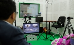 A studio engineer looks on as guest Chin Malin, spokesperson of Cambodia's Ministry of Justice, prepares for a VOD Roundtable program on judicial corruption, in Phnom Penh, Sept. 11, 2019. (Tum Malis/VOA Khmer)