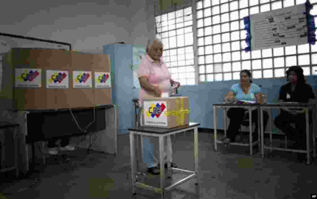 Seorang warga memasukkan kertas suara ke dalam kotak di tempat pemungutan suara di Caracas, Venezuela (14/4). (AP/Ramon Espinosa)