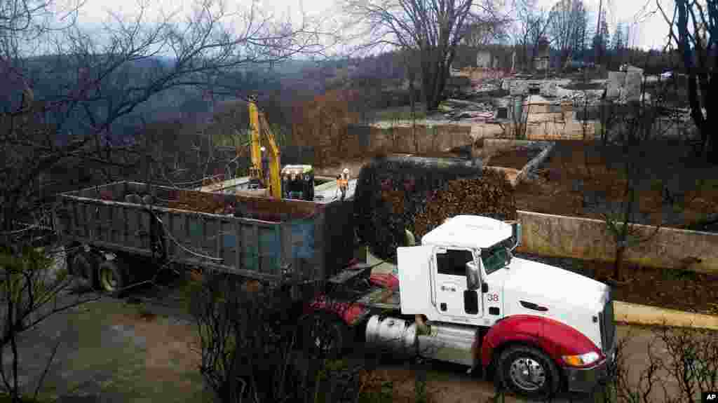 An excavator loads debris onto a truck, Feb. 8, 2019, while clearing a property burned by the Camp Fire in Paradise, Calif. Fears of harming an endangered frog species have forced crews to delay cleaning debris from about 800 properties in Paradise.
