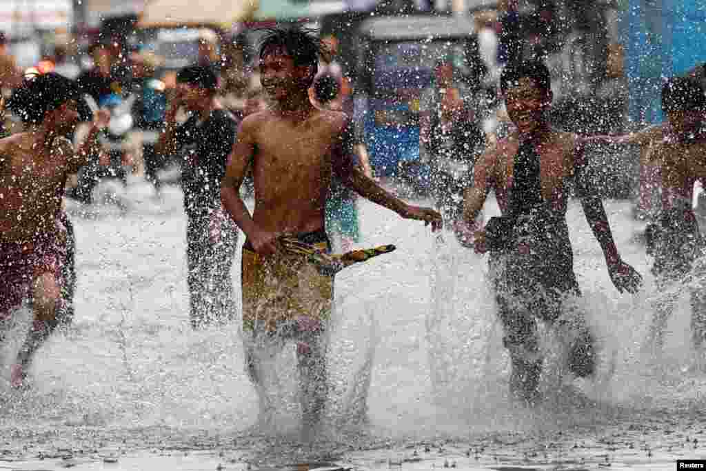 Youths play at a flooded area affected by rising sea levels and land subsidence, in North Jakarta, Indonesia.