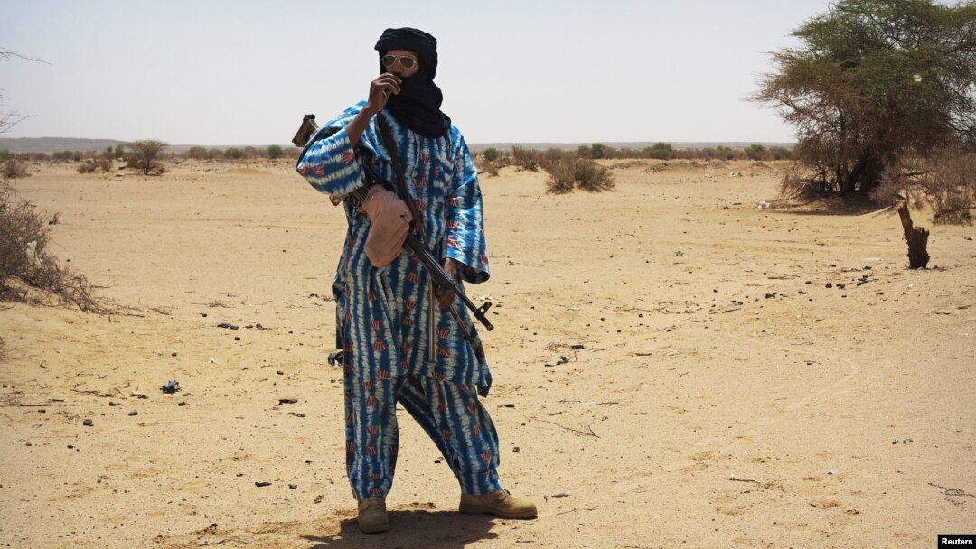 FILE - A fighter with the Tuareg separatist group MNLA stands guard outside the local regional assembly in Kidal, Mali, June 23, 2013. 