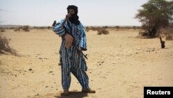 FILE - A fighter with the Tuareg separatist group MNLA stands guard outside the local regional assembly in Kidal, Mali, June 23, 2013. 