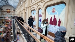 People stand in a queue to get a shot of Russia's Sputnik V coronavirus vaccine in a vaccination center in GUM State Department store in Moscow, Russia, Wednesday, Jan. 20, 2021. Russia started a mass coronavirus vaccination campaign on Monday, Jan…