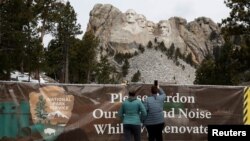 Visitors take a photos of the Mount Rushmore National Memorial in Keystone, South Dakota, April 16, 2020. 