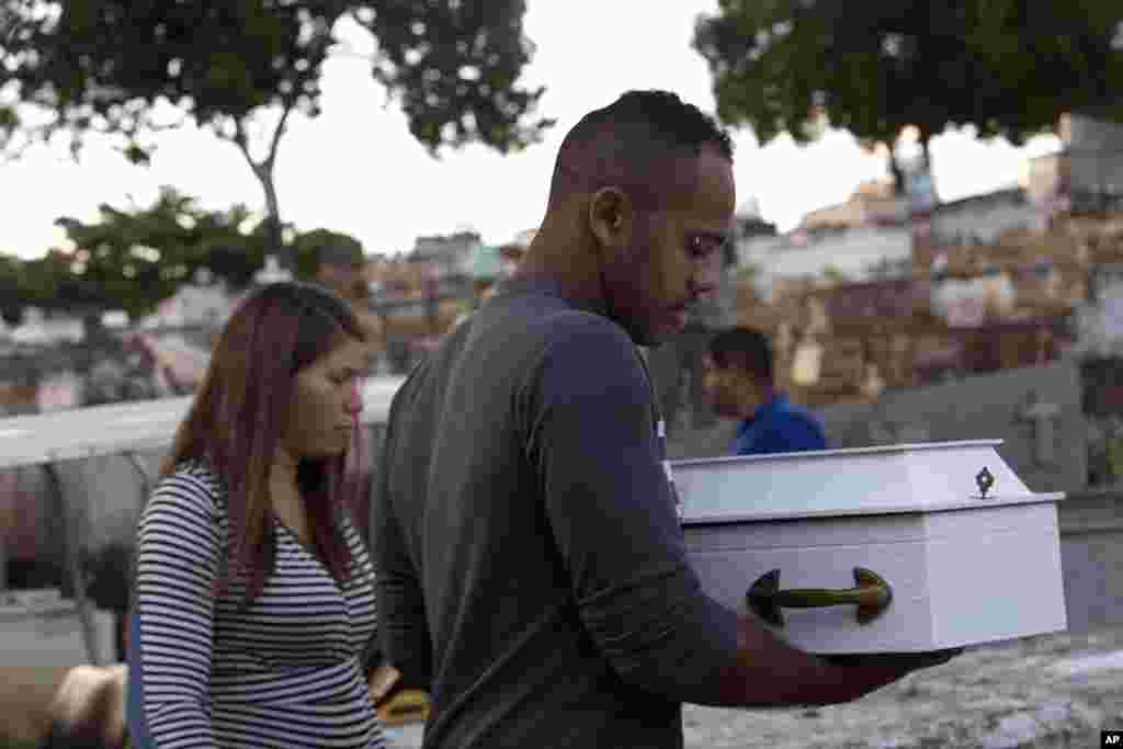 Claudineia dos Santos Melo (kiri) dan suaminya, Klebson Cosme da Silva membawa peti jenazah bayi mereka, Arthur Cosme, yang ditembak ketika masih berada di kandungan ibunya, dalam upacara penguburan di Rio de Janeiro, Brazil.