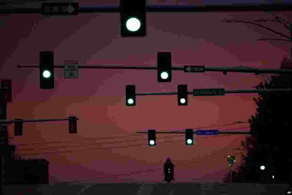 A motorcyclist drives on an empty street as the sun sets April 28, 2020, in downtown Topeka, Kansas.