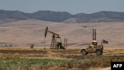 A US armoured vehicle drives past an oil field in the countryside of al-Qahtaniyah town in Syria's northeastern Hasakeh province near the Turkish border, on Aug. 4, 2020.