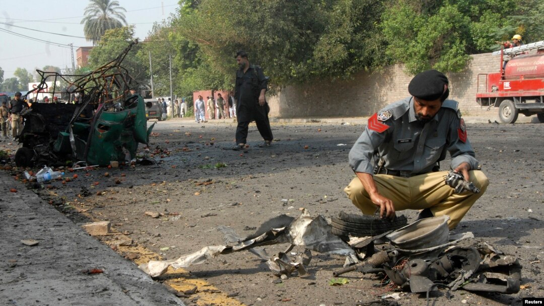 Seorang polisi tengah mengumpulkan barang bukti di tempat ledakan bon bunch dire di dekat sebuah konvoi Frontier Corps (FC) di Peshawar (23/9).