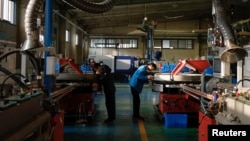 Workers monitor the production line of drip tape fittings at a factory of DAYU Water Group Co. in Jiuquan, Gansu province, China, Oct. 18, 2024.