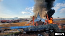 Para petugas damkar memadamkan api dari sebuah pesawat yang keluar dari landasan pacu saat mendarat di Bandara Internasional Muan, di Provinsi Jeolla Selatan, Korea Selatan, Minggu, 29 Desember 2024. (Foto: Yonhap via Reuters)