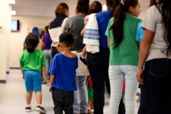 FILE - Mothers and children stand at South Texas Family Residential Center in Dilley, Texas, Aug. 9, 2018. Immigrant advocates are suing the U.S. government for allegedly detaining immigrant children too long and refusing to release them to family.
