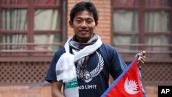 Japanese climber Nobukazu Kuriki poses with a Nepalese flag during a news conference in Kathmandu, Nepal, Aug. 23, 2015.