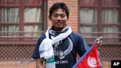 Pendaki asal Jepang Nobukazu Kuriki berpose dengan bendera Nepal dalam konferensi pers di Kathmandu, Nepal, 23 Agustus 2015. (AP/Bikram Rai)