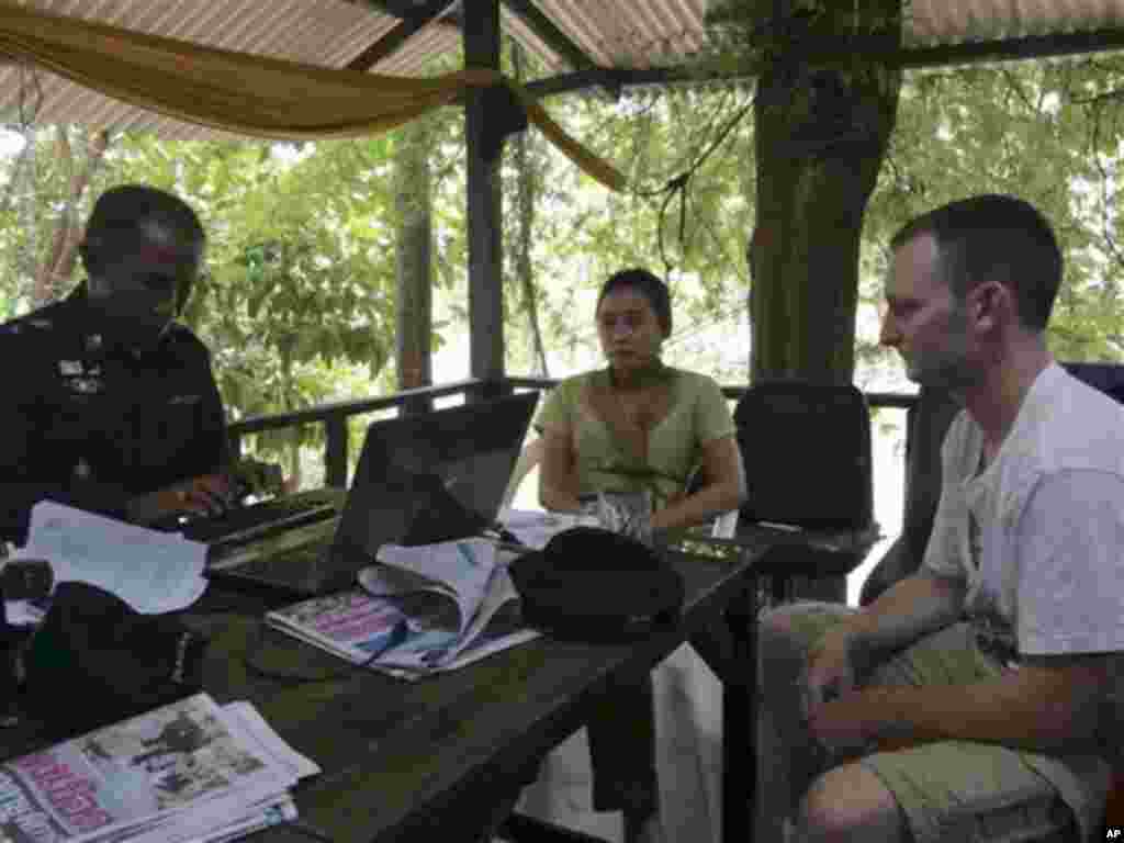 In this photo taken Tuesday, Sept. 16, 2014 and released by Royal Thai police, Christopher Ware, right, a British friend of British tourist David Miller who was killed along with his girlfriend, talks to a police officer during an investigation at a police station in the resort island of Koh Tao in the Gulf of Thailand. Police said Wednesday, Sept. 17 they have conducted autopsies on the two British tourists whose bludgeoned bodies were found on the island this week. (AP Photo/Royal Thai Police) 