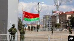 FILE - Belarusian Internal Ministry troops, with one soldier holding a Belarusian flag, guard a central area in Minsk, Belarus, Sept. 13, 2020. (TUT.by via AP)