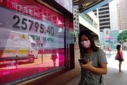 A woman walks past a bank electronic board showing the Hong Kong share index outside a Hong Kong local bank, Aug. 31, 2020.