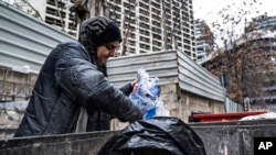 Hoda, 57, a Lebanese garbage scavenger, searches in a dumpster in Beirut, Lebanon, Saturday, Jan. 13, 2022.