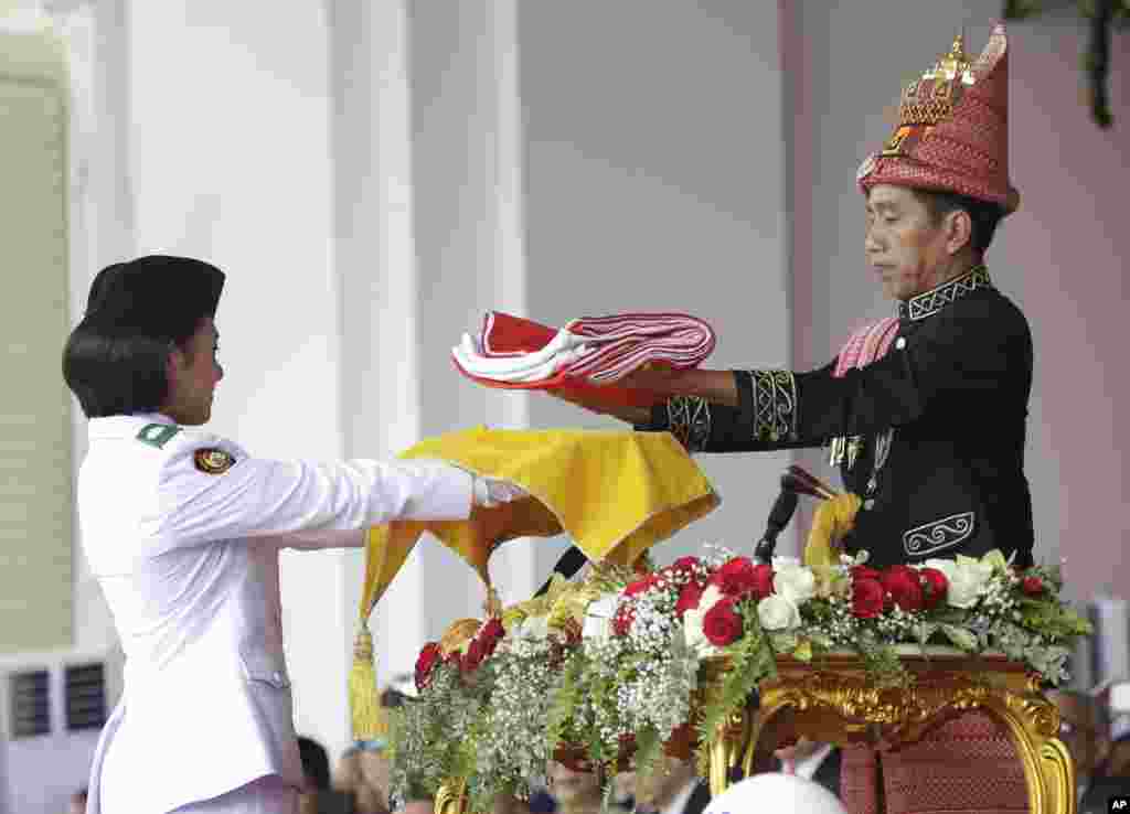 Presiden Joko Widodo (kanan) menyerahkan bendera Merah-Putih kepada anggota Paskibraka dalam upacara peringatan Ulang Tahun ke-73 Republik Indonesia di Istana Merdeka di Jakarta, Jumat, 17 Agustus 2018. (Foto: AP)