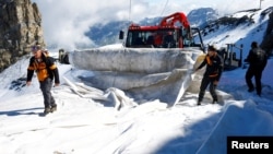 Employees of Titlis Bergbahnen cable car operator use a piste basher to transport blankets for the coverage o parts of the glacier to protect it against melting on Mount Titlis near the Alpine resort of Engelberg, Switzerland July 2, 2021. (REUTERS/Arnd Wiegmann)