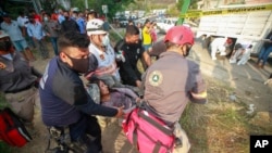 An injured migrant woman is moved by rescue personnel from the site of an accident near Tuxtla Gutierrez, Chiapas state, Mexico, Dec. 9, 2021. 