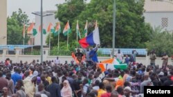 FILE - Hundreds of supporters of the coup gather and hold a Russian flag in front of the National Assembly in the capital Niamey, Niger July 27, 2023.