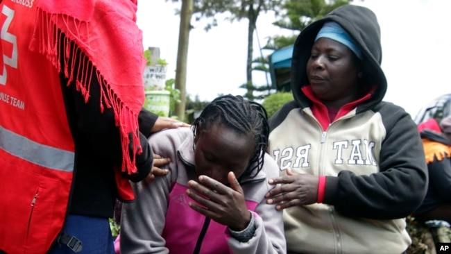 El personal de la Cruz Roja de Kenia y sus familiares intentan consolar a una mujer que reacciona cerca de un dormitorio quemado, luego de un incendio en la escuela primaria Hillside Endarasha en Nyeri, Kenia, el viernes 6 de septiembre de 2024.