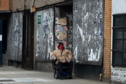 FILE - An African American man with a face mask navigates his wheelchair in Chicago's Hyde Park neighborhood, in Chicago, Illinois, April 6, 2020.