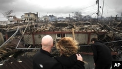 Una pareja se abraza mientras observan los escombros en Breezy Point, Nueva York, donde unas 110 casas fueron destruidas por el fuego, durante el paso de la tormenta Sandy.