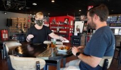 A customer being served a beer at Guitars &amp; Growlers in Richardson, Texas. The restaurant was opened to customers on May 1 after restrictions due to COVID-19 were eased.