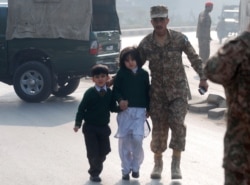 FILE - A soldier escorts schoolchildren from the Army Public School that was attacked by Taliban gunmen in Peshawar, Pakistan, Dec. 16, 2014.