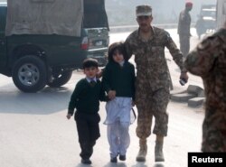 FILE - A soldier escorts schoolchildren from the Army Public School that was attacked by Taliban gunmen in Peshawar, Pakistan, Dec. 16, 2014.