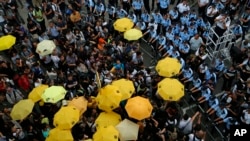 Protesters holding yellow umbrellas gather to observe a moment of silence to mark the first anniversary of "Umbrella Movement" outside the government headquarters in Hong Kong, Sept. 28, 2015. 