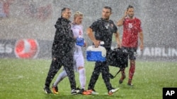 Soccer players leave the field after their match was suspended due to heavy rain, September 2016. (AP Photo/Hektor Pustina)