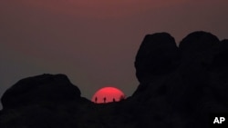 Excursionistas hacen una pausa para ver la puesta de sol en Papago Park durante una ola de calor donde las temperaturas alcanzaron los 115 grados Fahrenheit (46 grados Celsius) en Phoenix, el 15 de junio de 2021.