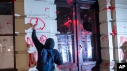 A protester paints graffiti on the City Hall building during a protest in Novi Sad, Serbia, Nov. 5, 2024.