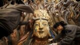 Restoration workers peel off loose gold foil as part of a restoration project for an 800-year-old Thousand-Hand Guanyin Buddhist statue on Mount Baoding in Chongqing municipality, China. The stone-carving statue, which takes up about 88 square metres on the mountain, dates back to the Southern Song Dynasty (1127-1279).