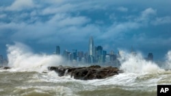 Waves crash over a breakwater in Alameda, California with the San Francisco skyline in the background on February 4, 2024. High winds and heavy rainfall are impacting the region. (AP Photo/Noah Berger)