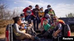 Familias y niños migrantes son trasladados en la parte trasera de un camión de la policía después de cruzar el río Grande hacia Estados Unidos desde México en Penitas, Texas, EE. UU., el 5 de marzo de 2021.