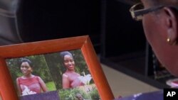 In this image taken from video, Margaret Ntale, whose three student daughters are stranded in Wuhan, China, looks at photographs of her children at her house in Kampala, Uganda, Feb. 27, 2020.