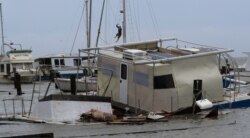 Matthew Howard sube al mástil de su barco mientras examina el daño a un puerto deportivo privado después de que fue golpeado por el huracán Hanna, el domingo 26 de julio de 2020, en Corpus Christi, Texas.
