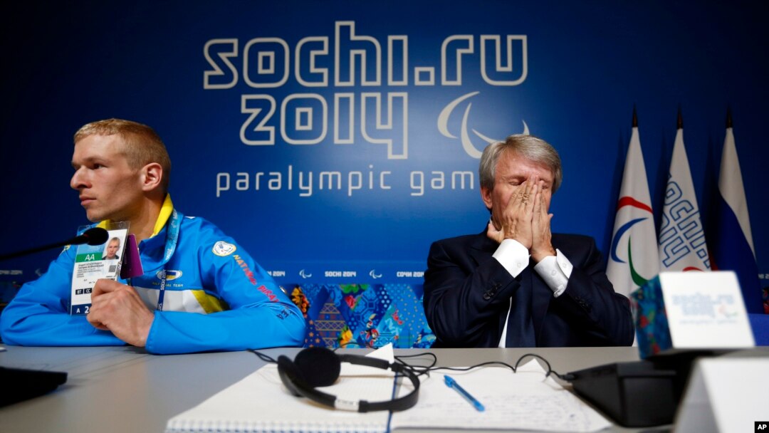 Atlet paralimpik Ukraina Grygorii Vovchinskyi menunjukkan tanda pengenalnya saat Presiden Komite Nasional Paralimpik Ukraina Valeriy Sushkevich menutup wajahnya dengan kedua belah tangannya dalam konferensi pers di Sochi (7/3).