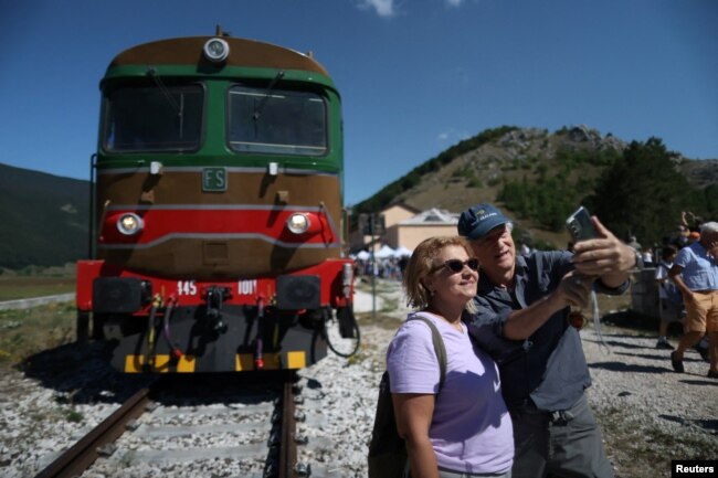 Passengers pose for a selfie picture in front of a vintage train in Palena, Italy July 21, 2024. (REUTERS/Antonio Denti)