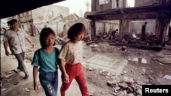 Warga etnis Tionghoa melewati rumah-rumah yang hancur dijarah dan dibakar massa dalam kerusuhan, 26 Mei 1998. (Foto: Reuters/Arsip)