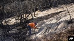 Workers secure a net to prevent mudslides over the burned side of a mansion in the Pacific Palisades neighborhood of Los Angeles, Jan. 24, 2025. 