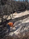 Workers secure a net to prevent mudslides over the burned side of a mansion in the Pacific Palisades neighborhood of Los Angeles, Jan. 24, 2025. 