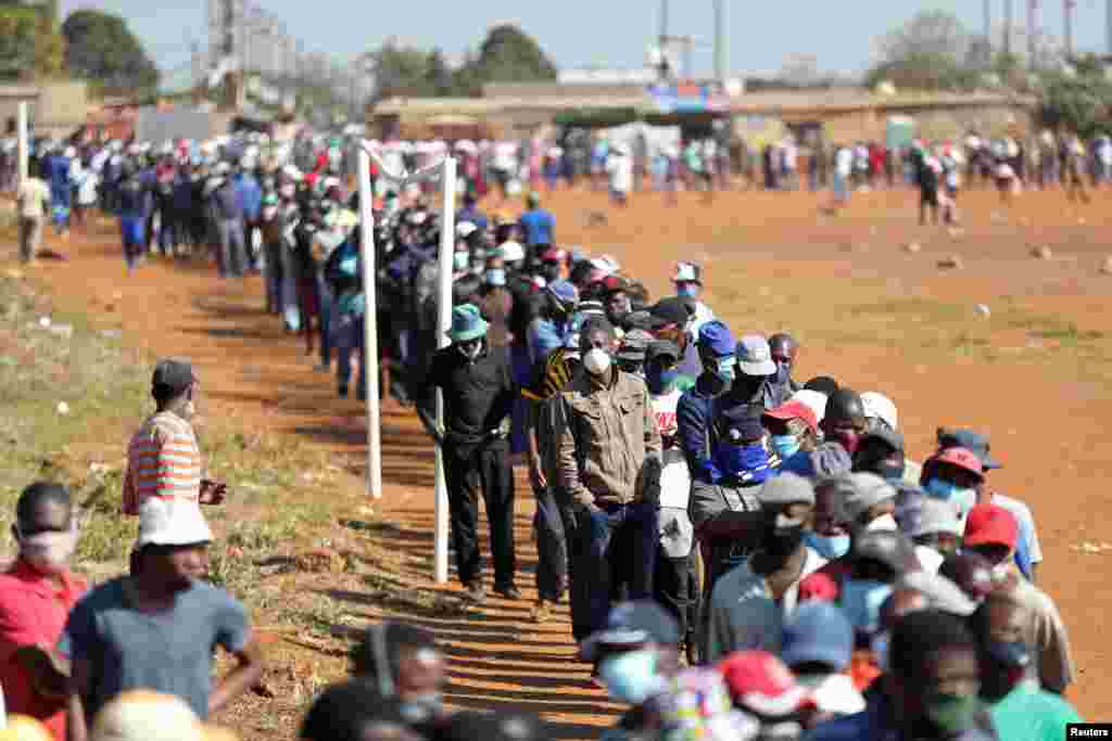 Pessoas com m&#225;scaras protetoras esperam numa fila para receber ajuda alimentar durante a dissemina&#231;&#227;o do surto de coronav&#237;rus (COVID-19), em Pret&#243;ria