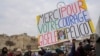 A man holds a placard reading 'Thank you for your courage Gisele Pelicot' outside the Avignon courthouse, southern France, Dec. 19, 2024. 