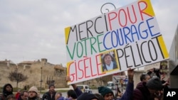 A man holds a placard reading 'Thank you for your courage Gisele Pelicot' outside the Avignon courthouse, southern France, Dec. 19, 2024. 