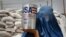 FILE - An Afghan woman carries a container of vegetable oil donated by United States Agency for International Development (USAID), in Kabul, Afghanistan, July 26, 2011.
