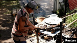 Un hombre cocina una pata de vaca en una casa ocupada por la comunidad Apacuana, en Caracas, Venezuela.